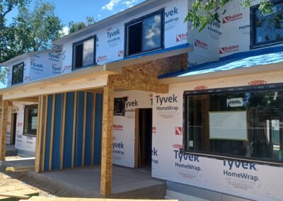 A house under construction with a wooden deck, showcasing the early stages of building process.