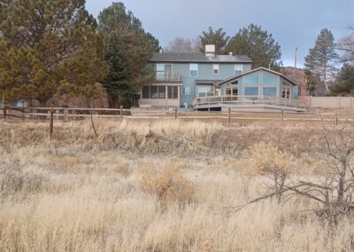 A solitary house surrounded by trees and grass in the middle of a vast field.